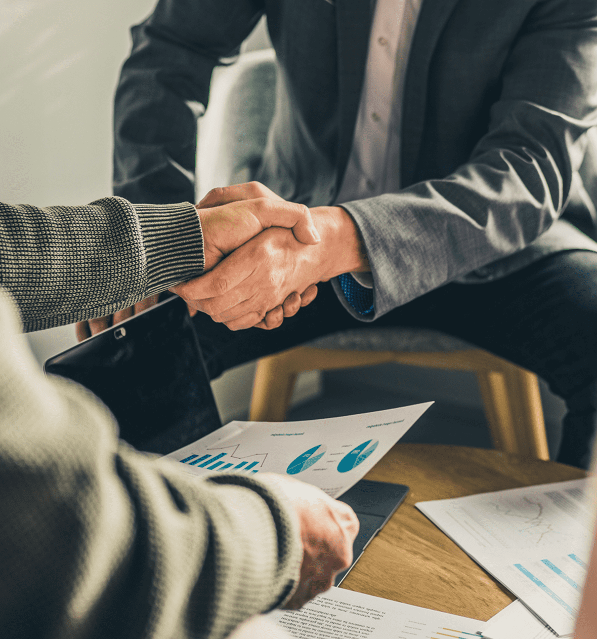 Handshake over business documents on table.
